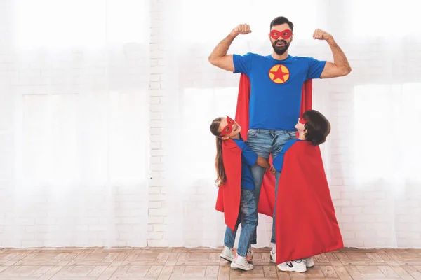 Vater mit Kindern in roten und blauen Superheldenanzügen. sie in Masken und Regenmänteln. — Stockfoto