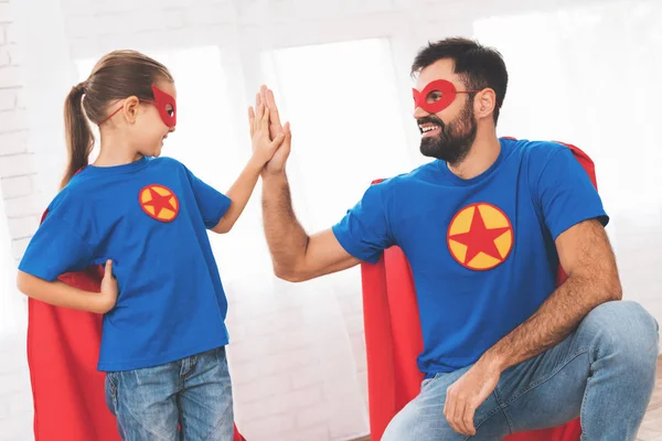 Padre con hija en trajes rojos y azules de superhéroes. Ellos en máscaras y impermeables . — Foto de Stock
