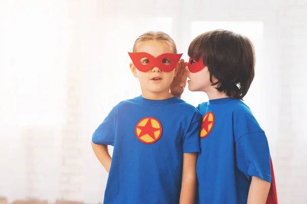 Kinder in den roten und blauen Anzügen von Superhelden. sie in Masken. Kinder posieren im hellen Raum. — Stockfoto