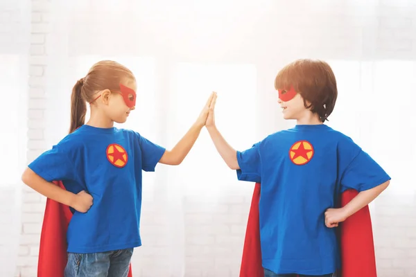 Kinder in den roten und blauen Anzügen von Superhelden. sie in Masken. Kinder posieren im hellen Raum. — Stockfoto