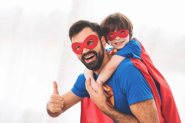 Père et fils dans les costumes rouges et bleus de super-héros. Sur leur visage il y a des masques et ils sont en imperméables . — Photo