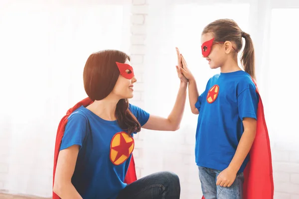 Madre con doughter en trajes rojos y azules de superhéroes. Ellos en máscaras y en impermeables . — Foto de Stock