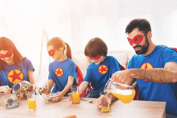 年轻的家庭在红色和蓝色的超级英雄的西装。他们的面孔在面具和他们在雨衣. — 图库照片
