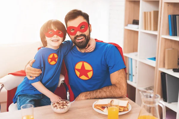 Père et fils dans les costumes rouges et bleus de super-héros. Sur leur visage il y a des masques et ils sont en imperméables . — Photo