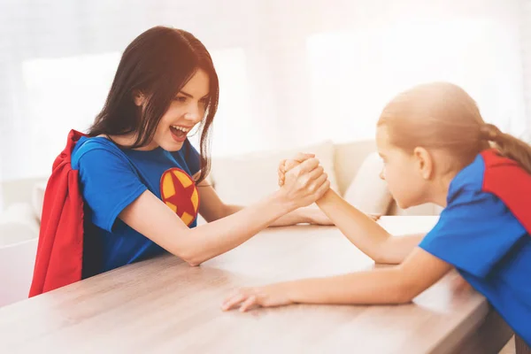 Mutter und Tochter in Superheldenkostümen. Sie messen sich im Armdrücken — Stockfoto