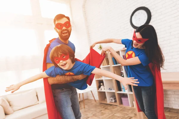 Madre, padre e hijo con trajes de superhéroes. Increíbles en una habitación luminosa . — Foto de Stock