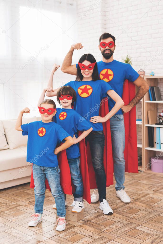 Young family in red and blue suits of superheroes. Their faces in masks and they are in raincoats.