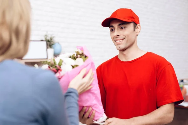 Man of Arab nationality works in the delivery of flowers. Woman received a bouquet of flowers home delivery — Stock Photo, Image