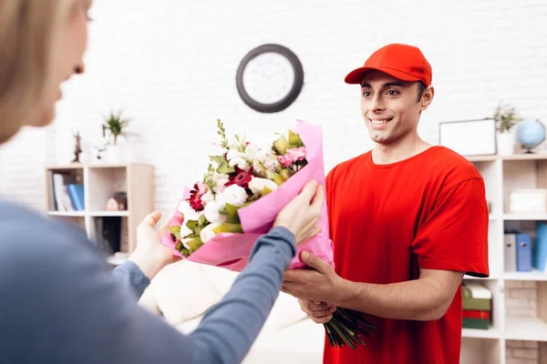 Man of Arab nationality works in the delivery of flowers. Woman received a bouquet of flowers home delivery