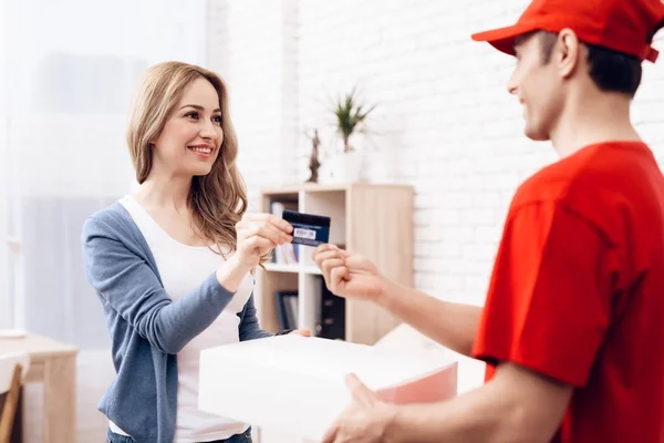 Die Frau erhielt das Paket vom Zusteller. Die Frau bezahlt den Zusteller. — Stockfoto