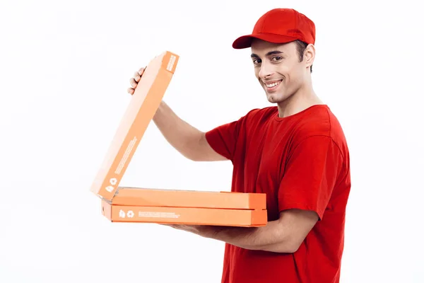 Hombre de apariencia árabe trabaja en la entrega de pizza. El hombre de uniforme rojo sostiene una caja de pizza . — Foto de Stock