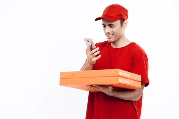 Mann arabischen Aussehens arbeitet in der Lieferung von Pizza. Mann in roter Uniform hält eine Schachtel Pizza in der Hand. — Stockfoto