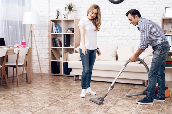 Un uomo che pulisce un aspirapolvere nella stanza di una donna. Handyman sta pulendo appartamento — Foto Stock