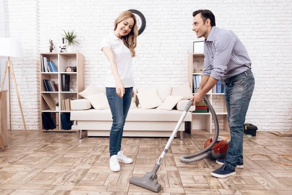 Un uomo che pulisce un aspirapolvere nella stanza di una donna. Handyman sta pulendo appartamento — Foto Stock