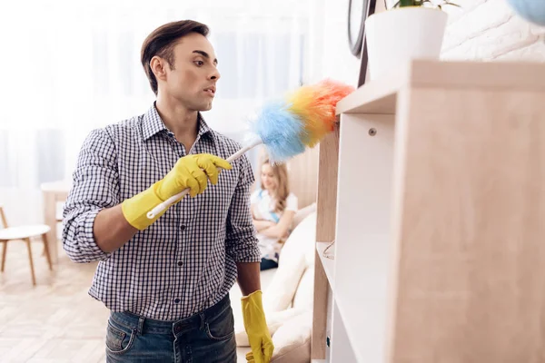 Man janitor wipes the dust in a woman's apartment with a brush. Handyman is cleaning the apartment — Stock Photo, Image