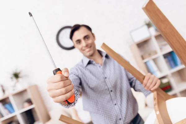 El hombre manitas se dedica a montar la silla. El reparador se dedica a reparar la silla . —  Fotos de Stock