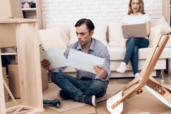 Man handyman is engaged in the assembly of furniture. Repairman is engaged in repairing furniture. — Stock Photo, Image