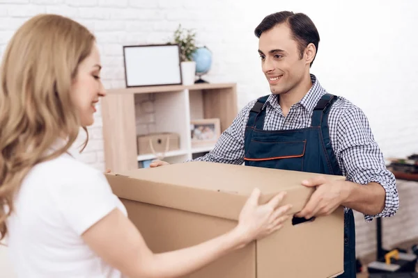 Woman received the parcel from the delivery worker. The loader man passes the boxes to woman.