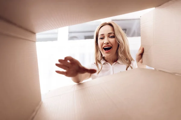 A woman looks into the empty box from the inside. Close-up photo of a woman peering into box. — Stock Photo, Image