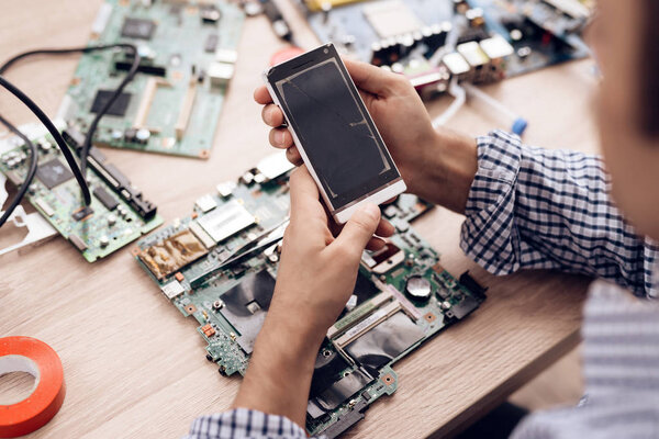 The man works as a radio technician. A man is repairing printed circuit board.