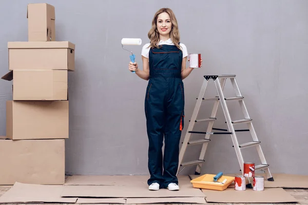 Una joven dirigiendo un pintor de casas. Una mujer se dedica a pintar las paredes . — Foto de Stock