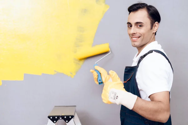 Man van Arabische verschijning werkt als schilder. Een man is schilderen muren. Hij draagt een speciaal uniform. — Stockfoto