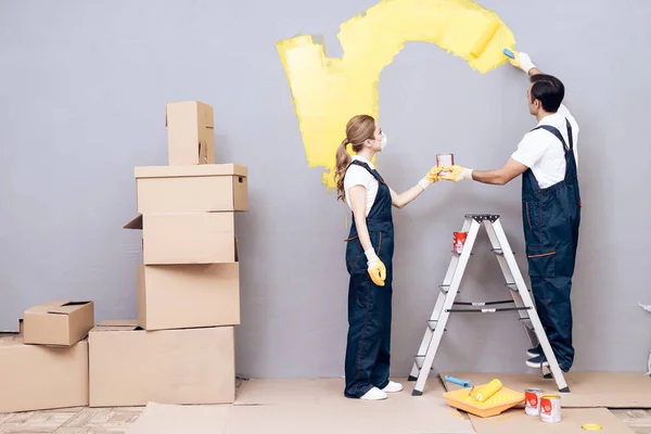 Jonge vrouw en een man van Arabische verschijning werkt als schilder. Een vrouw en een man zijn schilderij muren. — Stockfoto