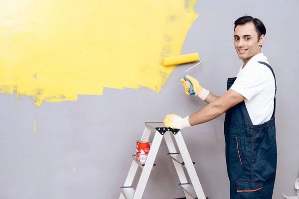 Muž z arabského vzhledu pracuje jako malíř. Člověk je malba stěn. Má na sobě speciální uniformu. — Stock fotografie