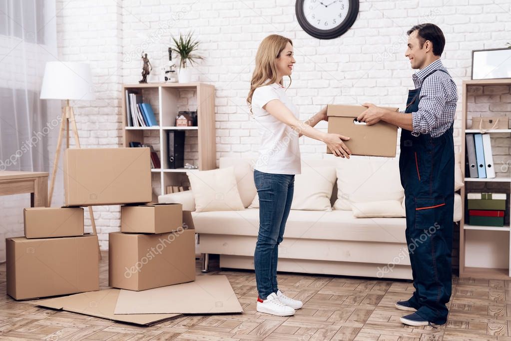 Woman received the parcel from the delivery worker. The loader man passes the boxes to woman.