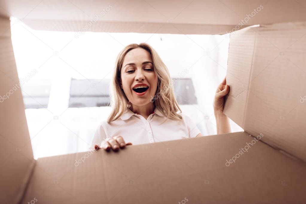 A woman looks into the empty box from the inside. Close-up photo of a woman peering into box.