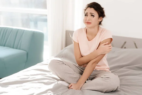 Una mujer solitaria está llorando sola, su rimel ha fluido. Se sienta en una cama en una habitación luminosa . —  Fotos de Stock