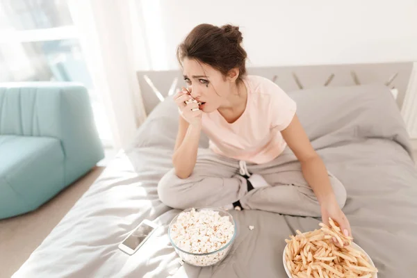 Una mujer solitaria está llorando sola, su rimel ha fluido. Se sienta en una cama en una habitación luminosa . — Foto de Stock