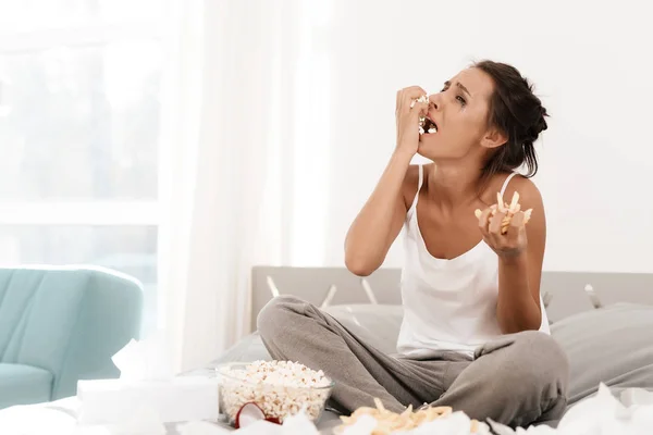 Eine einsame Frau weint allein, ihre Wimperntusche ist geflossen. sie sitzt auf einem Bett in einem hellen Zimmer. — Stockfoto