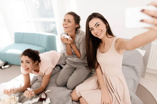 De meisjes zijn huilen bij de kip-partij. Ze zitten op het bed in de kamer. Meisjes maken selfie. — Stockfoto