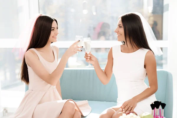 Cuidado previo a la boda. Chicas en una despedida de soltera. Se sientan en el sofá con una copa de champán . — Foto de Stock