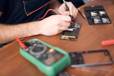 Bir adam bir cep telefonu onarıyor. Çerçeve, elleri ve tafsilât-in belgili tanımlık aygıt içinde.