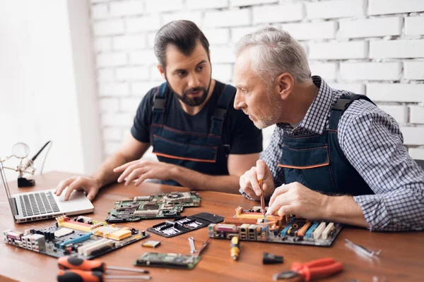 大人と若い男性は一緒にコンピューターから部品を修復します。. — ストック写真