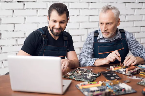 大人と若い男性は一緒にコンピューターから部品を修復します。. — ストック写真