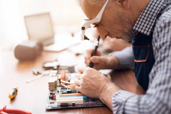 En äldre man reparerar en dator. — Stockfoto