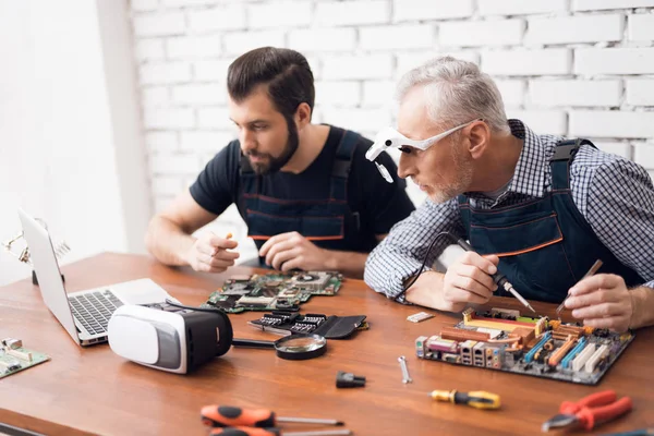 大人と若い男性は一緒にコンピューターから部品を修復します。. — ストック写真