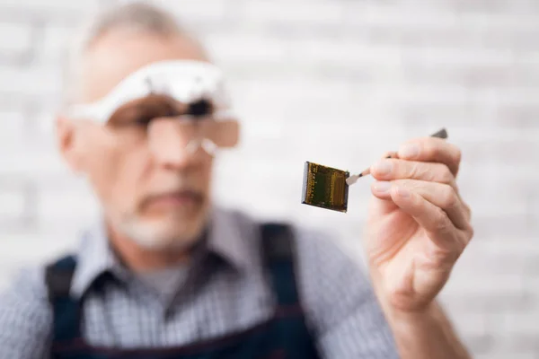 Ein älterer Mann betrachtet den Prozessor durch eine spezielle Brille. — Stockfoto
