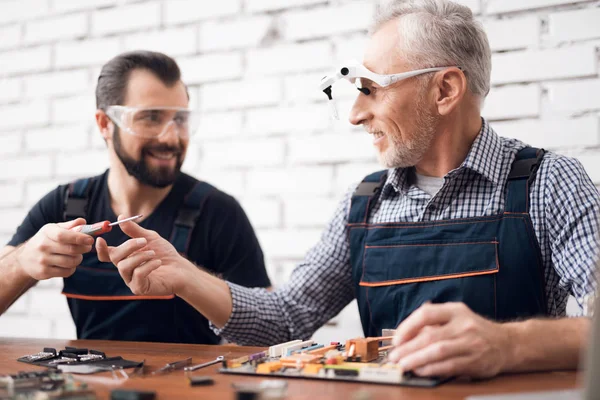 Ouderen en jonge mannen werken samen in een reparatiewerkplaats. — Stockfoto