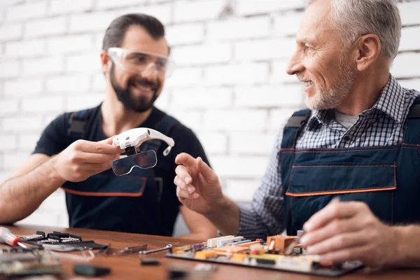 Ouderen en jonge mannen werken samen in een reparatiewerkplaats. — Stockfoto