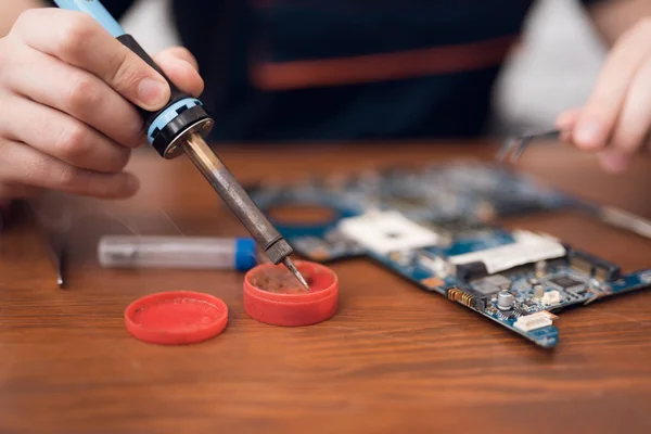 Ein Mann mit Lötkolben repariert Computergeräte. — Stockfoto