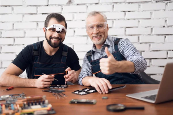 Elderly and young men repair a mobile phone together. — Stock Photo, Image