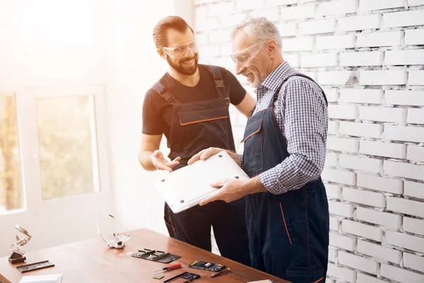 Alte und junge Männer untersuchen gemeinsam einen Laptop. — Stockfoto