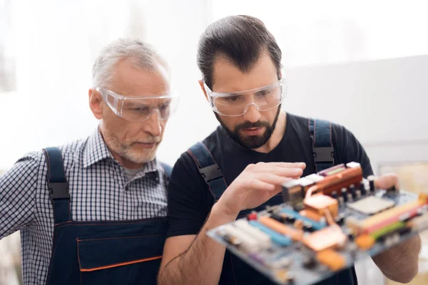 Äldre och unga män titta tillsammans på detaljerna i den bärbara datorn. — Stockfoto
