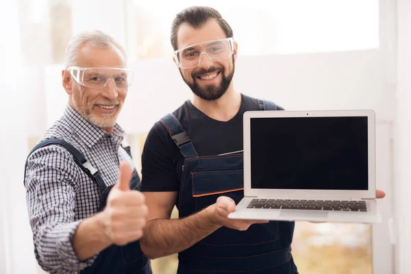 Ouderen en jonge mannen poseren samen op de camera met een laptop. — Stockfoto