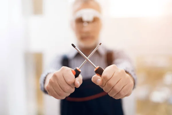 Ein älterer Mann posiert mit einem Schraubenzieher vor der Kamera. — Stockfoto