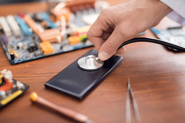 Ein Mann im weißen Laborkittel hört Computergeräte durch ein Stethoskop. — Stockfoto